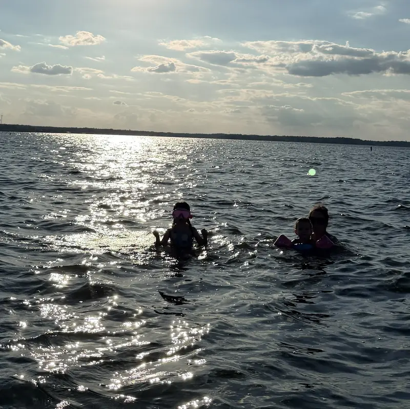 Two swimmers silhouetted in the sparkling water of Lake Conroe at golden hour near the Veranda V22RC