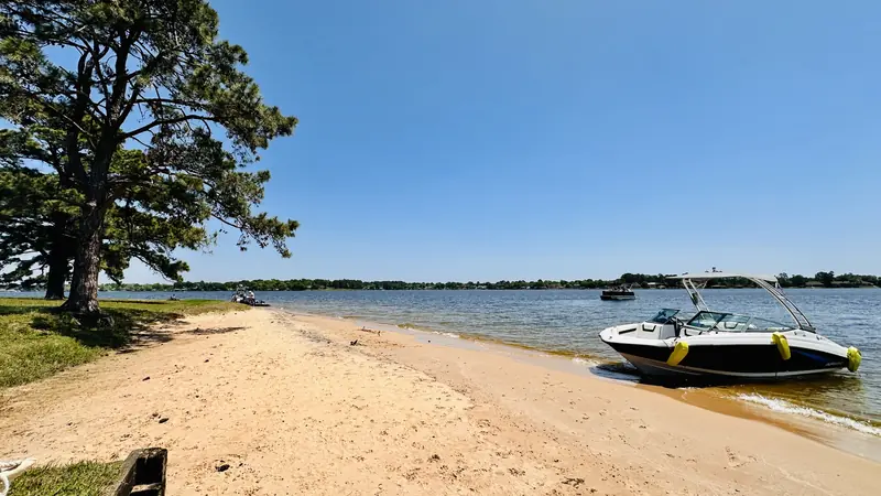 Sandy beach on Lake Conroe with a large tree overhead and the Yamaha AR190 pulled up at the water’s edge
